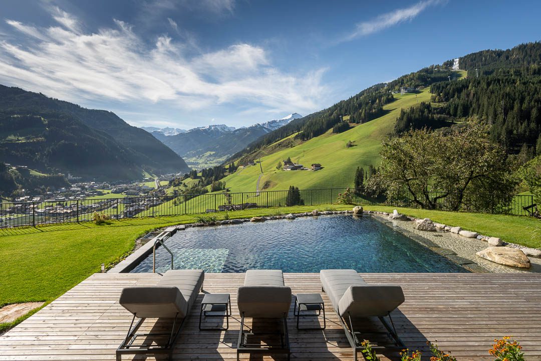 Moderne Außenansicht des Bergengut Großarl mit Schwimmteich und Bergblick, fotografiert vom Hotelfotografen Lorenz Masser.
